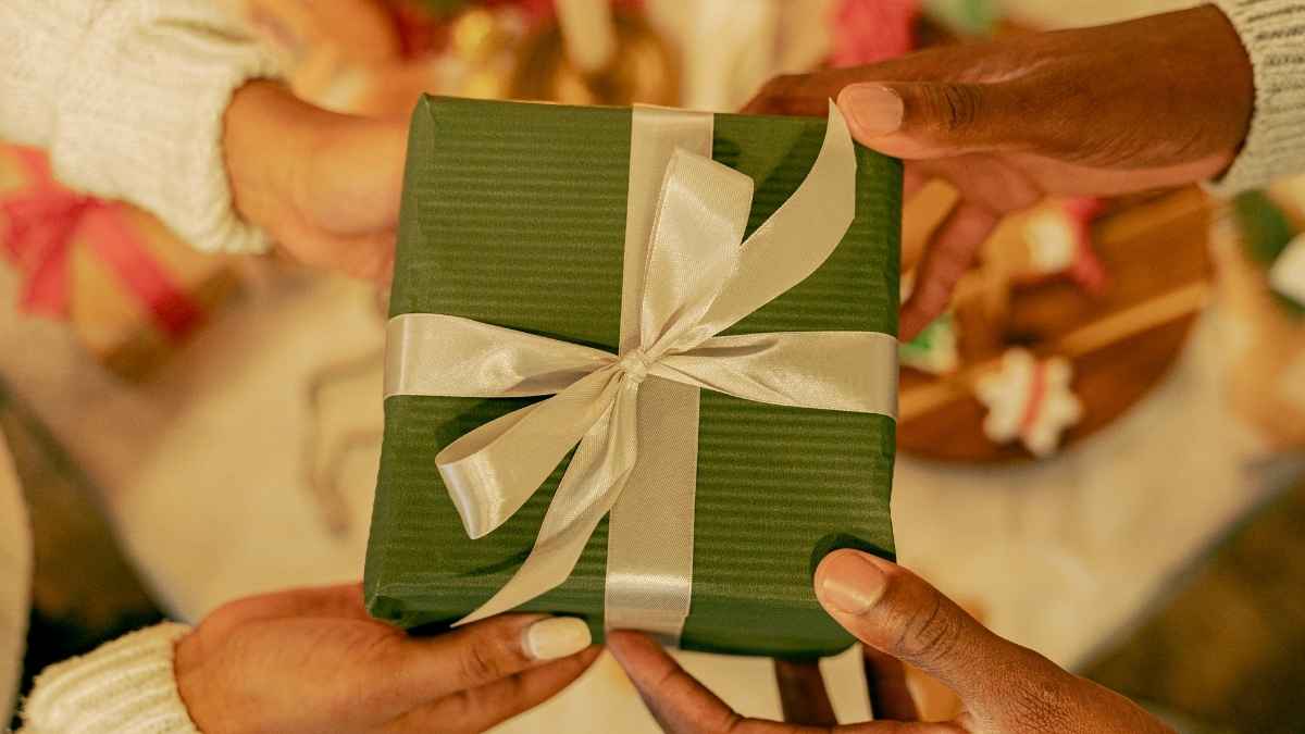 Échange d’un cadeau de Noël joliment emballé dans un ruban, scène chaleureuse et festive.